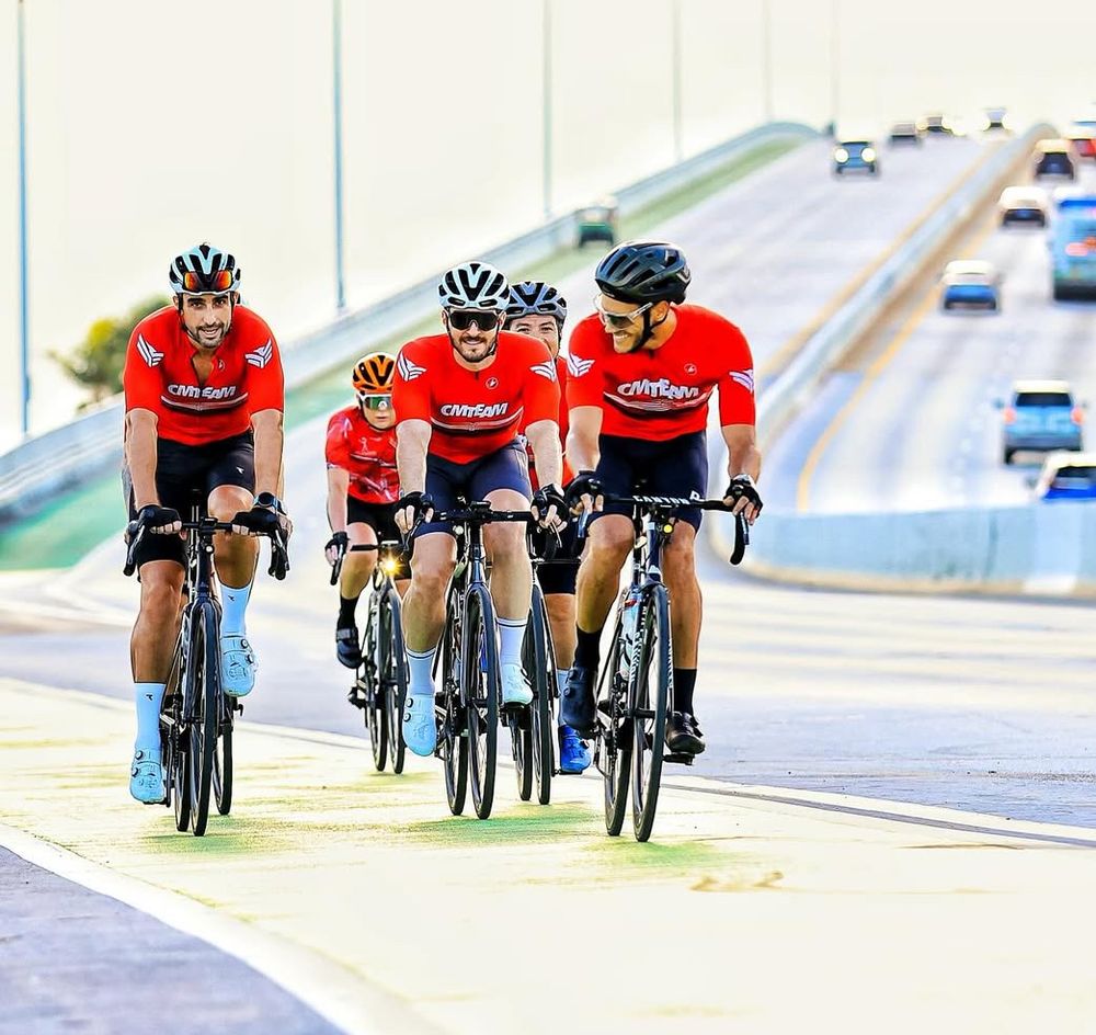 Atletas da CMTeam pedalando juntos na ponte, em Miami